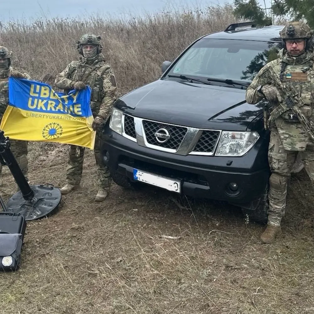 Ukrainian defenders holding a Liberty Ukraine flag in front of a delivered pickup